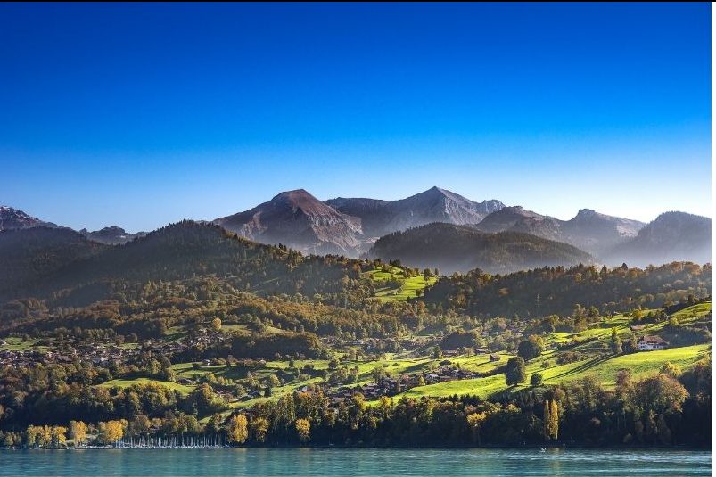 Green mountains overlooking a lake with a bright blue sky