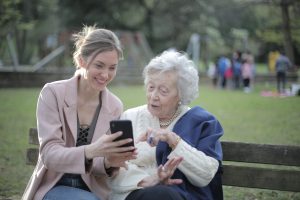 Cheerful senior mother and adult daughter using smartphone together. Choosing a phone for older people with sight loss