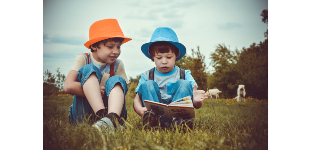 Two young boys reading a book in a field