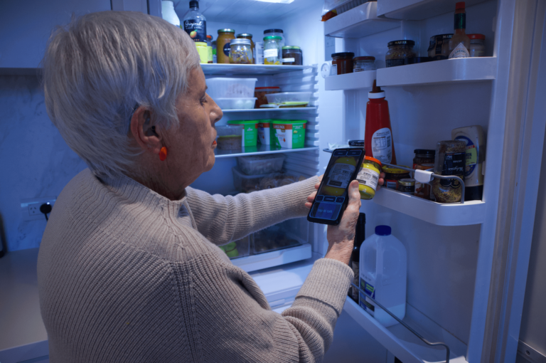 Lady with grey hair using RealSAm Pocket Plus to identiify items in her fridge