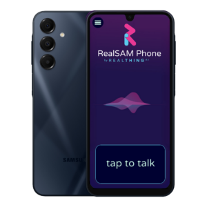An image of the front and back of the A16 Samsung Galaxy model. The screen displays the ‘tap to talk button’ and the words ‘RealSAM Phone by RealThing Ai’ below the RealThing logo. The background of the screen is a deep purple— navy blue gradient.