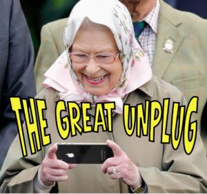 A playful image showing Queen Elizabeth II smiling as she looks down at a smartphone in her hands. She is wearing a headscarf, glasses, and a beige coat. Bold yellow comic-style text across the image reads ‘THE GREAT UNPLUG’, giving a humorous tone.
